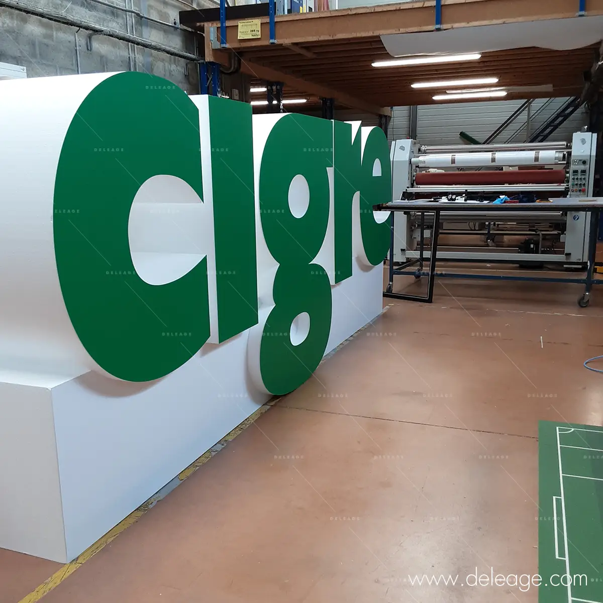5-logo-polystyrene-facing-pvc-vert-atelier Logo CIGRE en polystyrène blanc habillé d'un facing PVC vert, vue de biais dans l'atelier DELEAGE